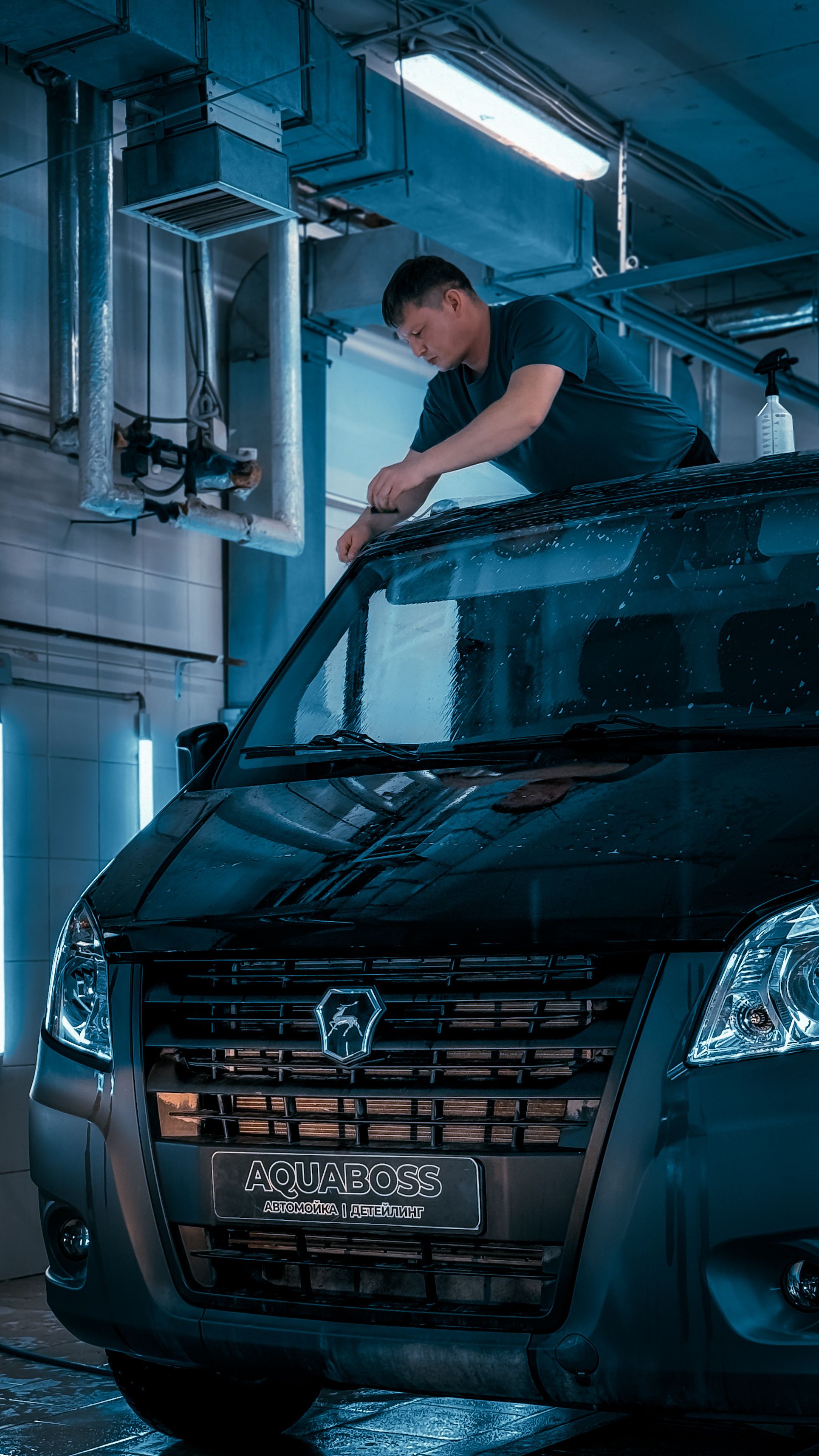 Professional detailer cleaning a commercial van in a wash bay